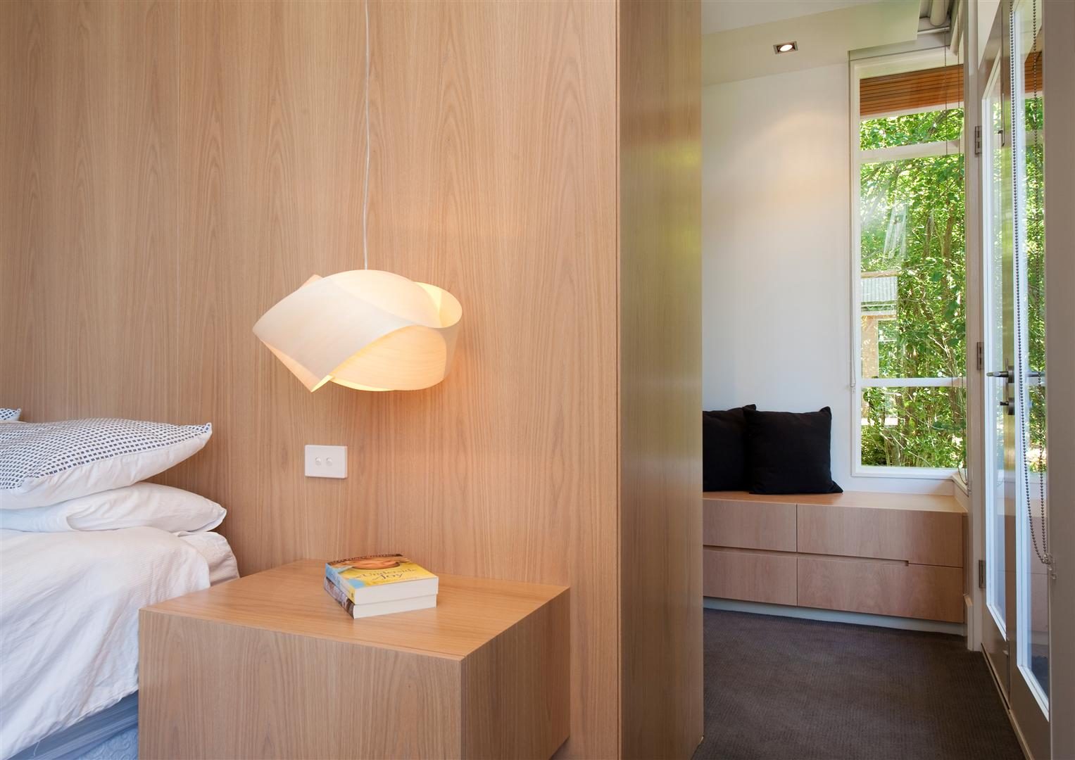Bedroom — bed and a window seat in timber, opening to the garden