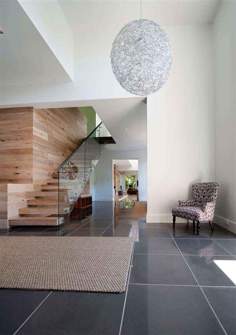 Entry void — a floating timber stair rising through a double-height white space under a spherical pendant