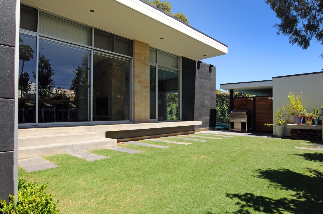 Garden elevation — charcoal masonry, sandstone and floating roofline