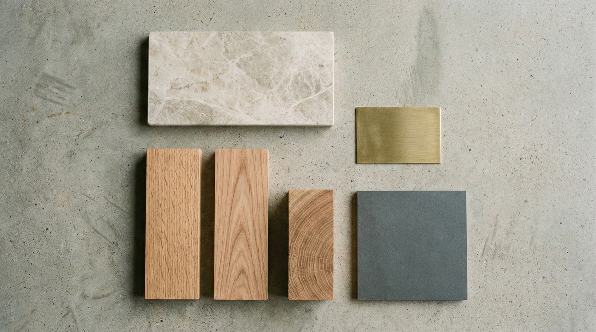 Material palette — marble, brass, timber and stone samples laid out on raw concrete